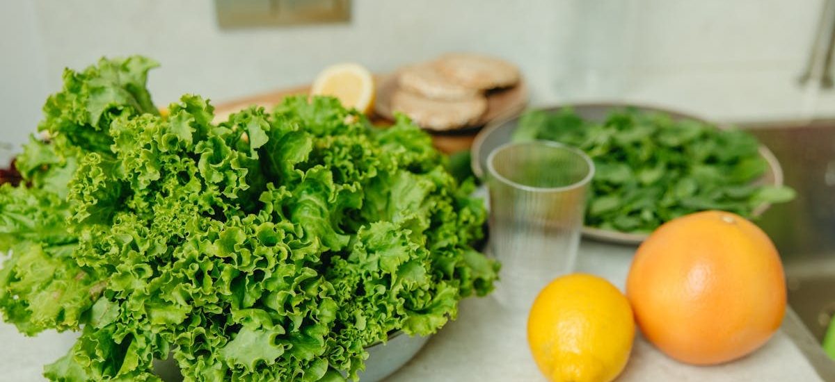 A vibrant display of fresh green lettuce and citrus fruits on a kitchen table.