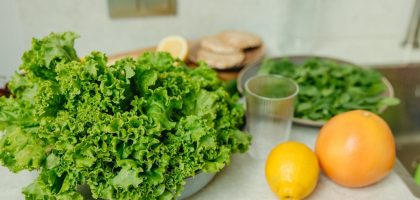 A vibrant display of fresh green lettuce and citrus fruits on a kitchen table.