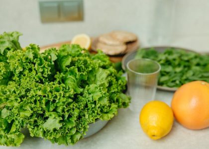 A vibrant display of fresh green lettuce and citrus fruits on a kitchen table.